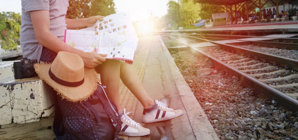 young man traveler with backpack and hat at the train station with a traveler , travel and recreation concept